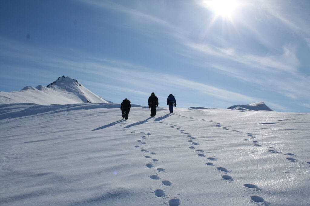 Three people on a ski tour across the snow near Ny-Ålesund